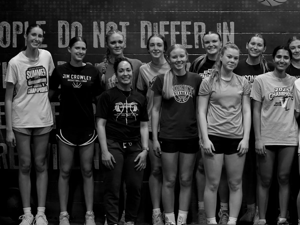 High-school training group with Hoops Strength coaches in front of the gym mural